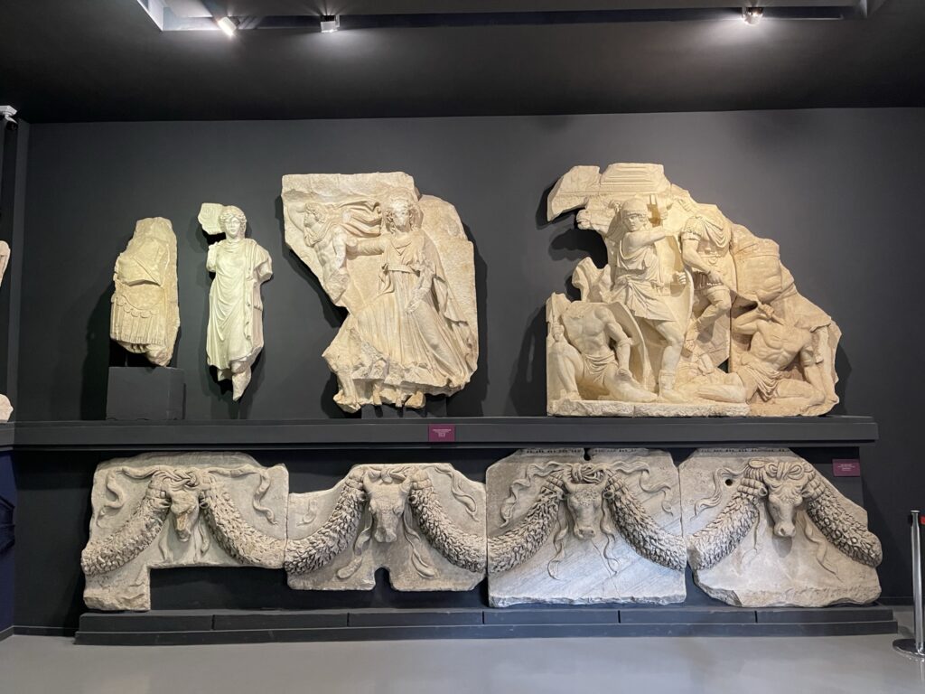 Partial reliefs made of white marble depicting soldiers, civilians and oxes