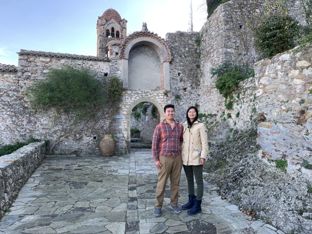 A man and a lady standing in front of a stone built church